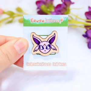 Pin de madera con diseño de la cara de Espeon, en su packaging.