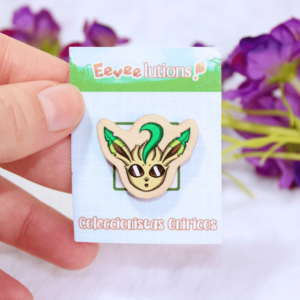 Pin de madera con diseño de la cara de Leafeon, en su packaging.