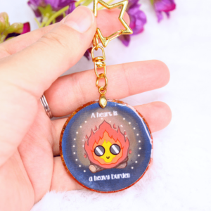 Llavero de resina con forma circular, con la cara de Calcifer.