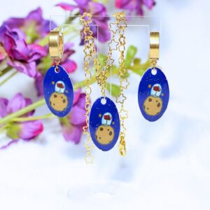 Conjunto de pendientes de aro pequeños dorados y pulsera de color dorado con eslabones con forma de estrella, conjunto inspirado en El Principito, con abalorio que incluye una ilustración del asteroide y la rosa.