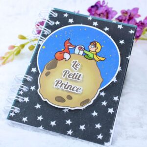 Cuaderno A6 inspirado en El Principito. Portada en relive con el Principito, el Zorro, la rosa y el asteroide. Frase en relieve "Le Petit Prince".