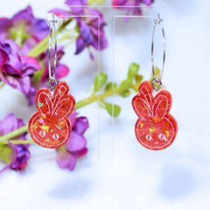 Pendientes de aro de color plateado con pieza de resina en color rojo con purpurina, en forma de cerenejito (fusión entre cereza y conejito).
