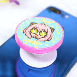 Pop socket de resina rosa con ilustración inspirada en Anya con expresión sorprendida diciendo "waku waku".